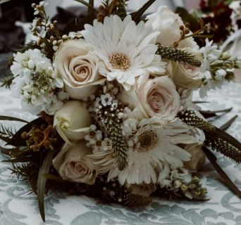 Neutral bouquet of cream roses, white gerberas, dried grasses and feathers