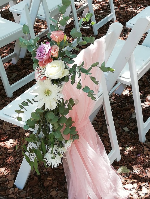 Wedding aisle chairs dressed with fresh flowers and pink draped fabric