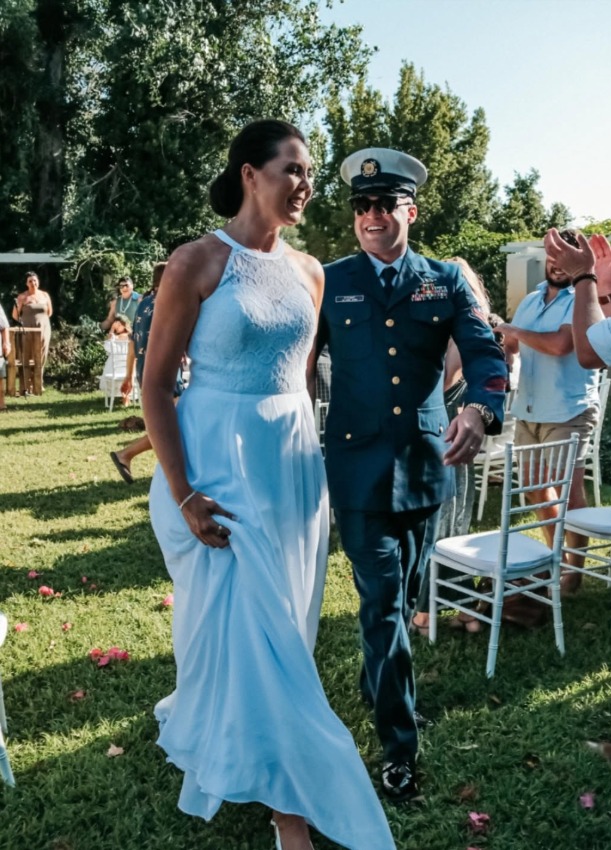 Bride and groom walking down a garden aisle past white ceremony chairs