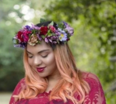 Portrait of a woman wearing a rich purple and red fresh flower crown