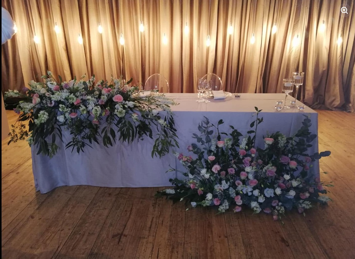 Wedding head table with cascading florals and warm candlelight