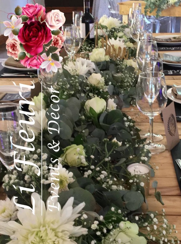 White roses, chrysanthemums and greenery forming a floral runner along a wooden reception table